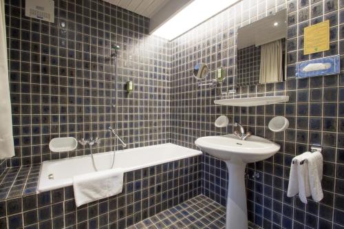 因斯布鲁克加尼罗密霍夫酒店的蓝色瓷砖浴室设有水槽和镜子