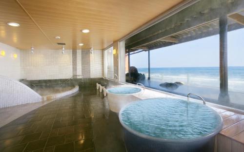 铫子市犬吠先观光酒店的一间带两个浴缸的浴室,享有海景