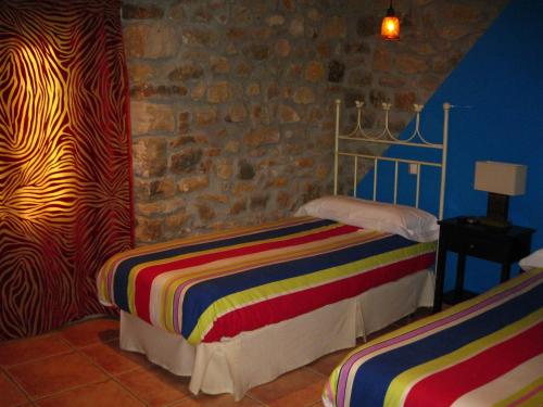 QuintanaentelloHotel La Pradera de Marta的一间卧室设有两张床和石墙