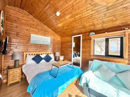 Malin HeadCosy Portmor Log Cabin- Sea views, Deck & Relaxation的一间卧室配有一张床、一张桌子和一张沙发