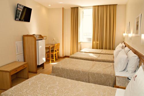 里约热内卢Hotel Regina Rio de Janeiro的酒店客房设有两张床和一张桌子。