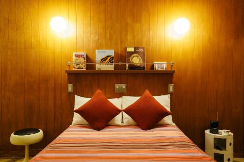北中城村冲绳斯佩斯汽车旅馆的一间卧室配有带橙色枕头的床和木墙