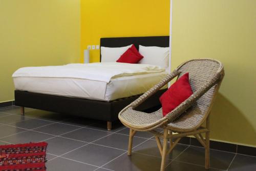拉希迪耶奥博格提尼特民宿的一间卧室配有一张床和一把带红色枕头的椅子
