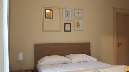 布德瓦Apartments Fortunella的一间卧室配有一张带白色枕头的床,墙上挂有图片