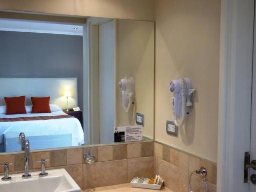 马德普拉塔Villa Nuccia Hotel Boutique的一间带水槽和镜子的浴室以及一张床