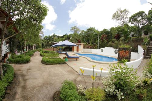 阿约拉港Piedras Blancas Lodge的后院设有游泳池、长凳和遮阳伞