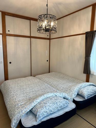 下关Guest House "Ro"kumano的一间卧室配有一张床和一个吊灯