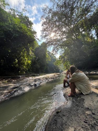 坎古Nunu Bali Eco Friendly Retreat的两个人坐在河边的岩石上