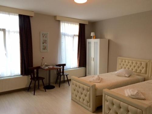 布鲁塞尔信誉公寓的一间卧室配有两张床、一张桌子和一张书桌