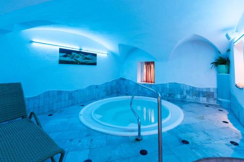 蒙圭尔福金色玫瑰酒店的一间设有浴缸的大浴室,位于一间蓝色灯光的房间