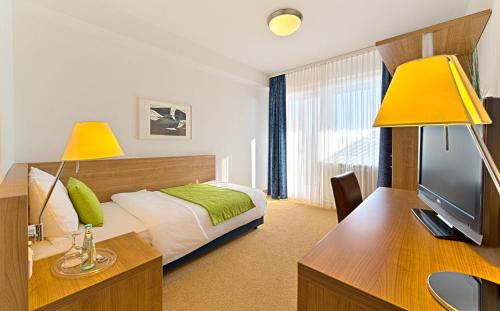巴特塞京根Sapia Hotel St. Fridolin的一间卧室配有一张床和一张书桌及电视