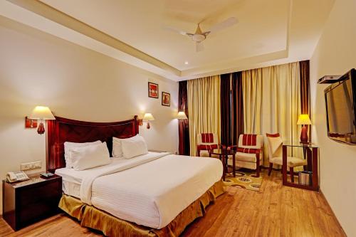 新德里Hotel Tej View Near Delhi Airport的酒店客房带一张床、一张桌子和椅子