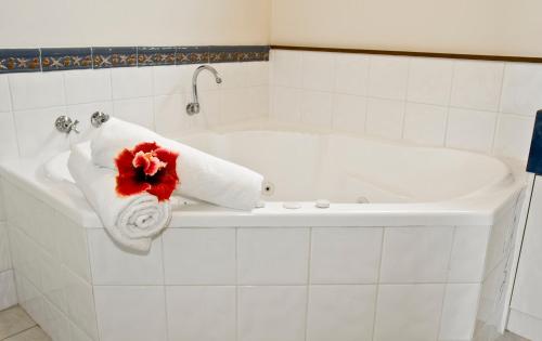 彭特派因州长住宿度假酒店的白色浴缸,上面有毛巾和红花