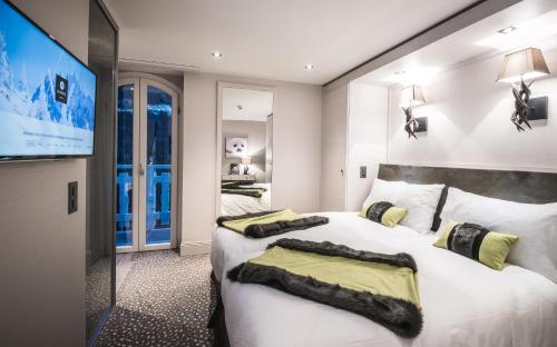 尚佩里Hôtel Le White - Le 42 Restaurant的一间卧室配有两张床和一台平面电视
