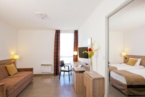 马诺斯克Apparthotel Séjours & Affaires Manosque的酒店客房,配有床和沙发