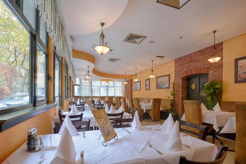 贝尔格莱德尔格莱德市酒店的餐厅设有白色的桌椅和窗户。