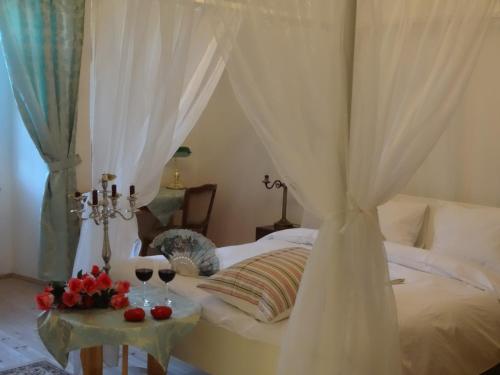 Krompachy卡斯缇尔比拉达玛赛纳瑞缇尔酒店的一间卧室配有一张带两杯葡萄酒的天蓬床。