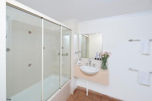 汤斯维尔雷吉斯锚地公园酒店的一间带玻璃淋浴和水槽的浴室