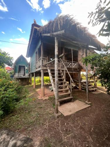 OBT Homestay and Bungalows的茅草屋顶和楼梯的房子