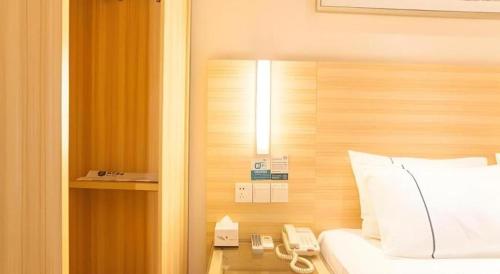 南宁City Comfort Inn Nanning Chaoyang Square Metro Station的一间酒店客房,配有一张床和一部电话