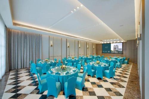 深圳Seaview Gleetour Hotel Shenzhen Eastwing building的宴会厅配有蓝色的桌椅