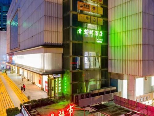 合肥Vatica Hotel Hefei Luyang District Suzhou Road Provincial Hospital的一座高大的建筑,旁边是绿灯