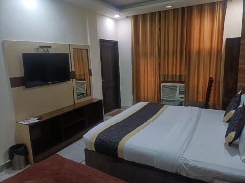 新德里Hotel Green tark Near IGI Airport Delhi的配有一张床和一台平面电视的酒店客房