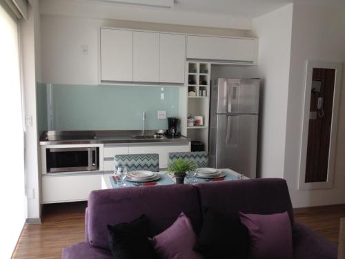 圣保罗Estúdio Vila Madalena的一间带紫色沙发的客厅和一间厨房