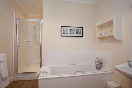 Bridgend斯科罗斯别墅酒店的白色的浴室设有浴缸和淋浴。
