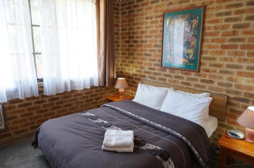 克兰伯恩红木公园汽车旅馆的一间卧室配有一张砖墙床