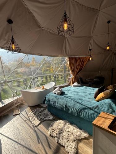 BălanGreen Garden Glamping Retezat的一间带浴缸、床和窗户的卧室