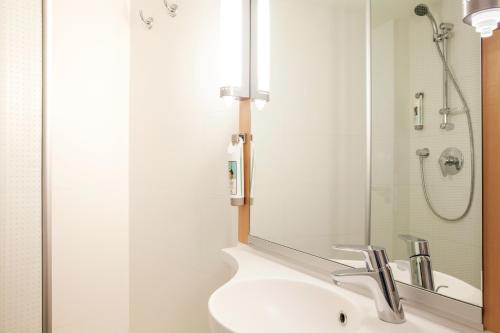 巴塞尔巴塞尔班霍夫宜必思酒店的浴室配有盥洗盆和带镜子的淋浴