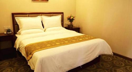 常州GreenTree Inn Jiangsu Changzhou Henglin Town Shuntong Road Express Hotel的卧室配有一张带白色床单和枕头的大床。