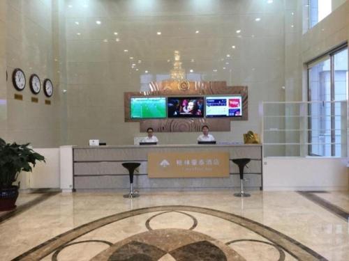 唐山GreenTree Inn Tangshan Xueyuan Road Business Hotel的两人坐在大堂的柜台