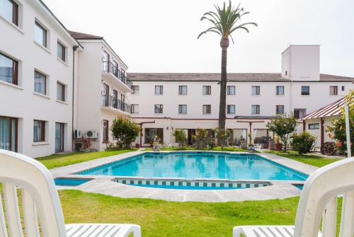 拉塞雷纳弗朗西斯科德阿吉雷酒店的一座带两把椅子和一棵棕榈树的建筑的庭院内的游泳池