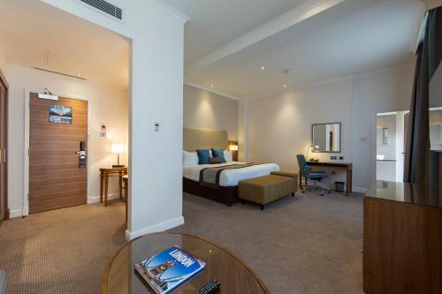 伦敦Thistle London Piccadilly的酒店客房配有一张床铺和一张桌子。