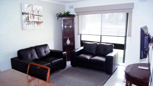 谢珀顿莫德圣公寓的客厅配有两张真皮座椅和一张桌子