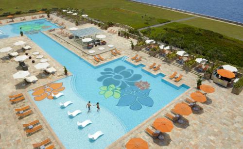 马尼拉Solaire Resort Entertainment City的享有带遮阳伞和椅子的度假村游泳池的空中景致