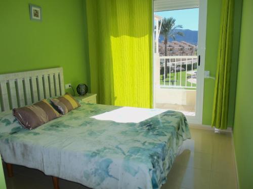 德尼亚Playa Sol Mediterranea的一间卧室设有一张带绿色墙壁和窗户的床。