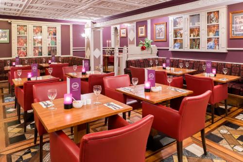 卡斯莱兰河岛酒店的餐厅设有木桌、红色椅子和紫色墙壁