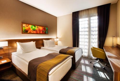 伊斯坦布尔伊斯坦布尔卡德柯伊假日酒店的酒店客房配有两张床和一张书桌