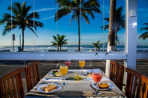 瓜鲁雅Strand Hotel Guarujá Frente Mar的海滩阳台的桌子上摆放着食物和饮料