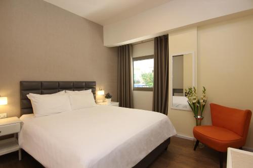 特拉维夫艾德尔森酒店 的卧室配有白色大床和橙色椅子