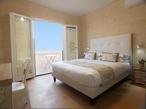 加拉GozoWindmill Apartments的一间卧室设有一张大床和一个大窗户