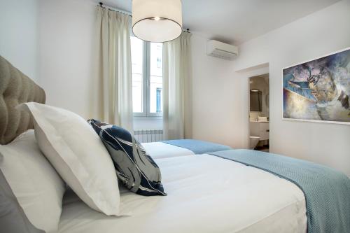 马德里奥古斯托慢慢套房公寓的一间卧室配有带白色床单和枕头的床。