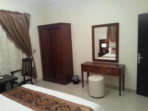 塞卡凯Lara Al Jawf Hotel Apartments的一间卧室配有一张床、梳妆台和镜子