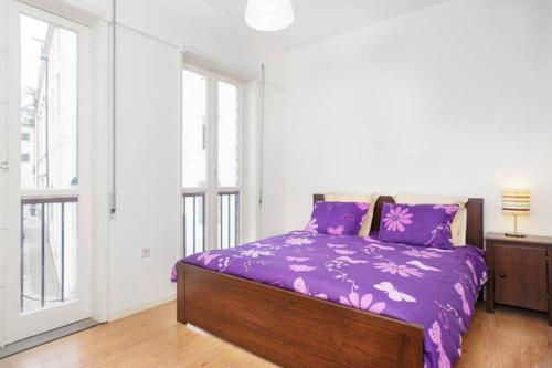 波尔图奥珀多姆斯酒店的一间卧室配有一张带紫色床单和窗户的床。
