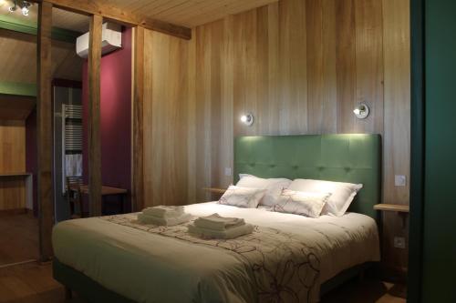 Saint-Michel-Saint-JaymesB&B La Ferme de la Patte d'Oie的一间卧室配有一张大床和绿色床头板
