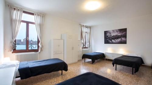 威尼斯丝绸之路旅舍的一间卧室设有两张床和窗户。
