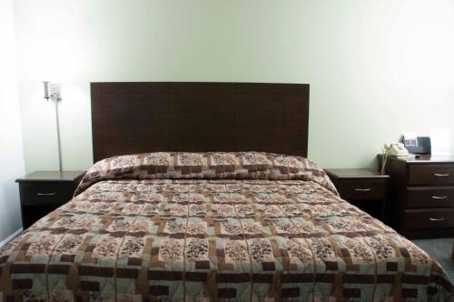 MaconTravelier Motel - Macon的卧室内的一张床位,配有两张梳妆台和床罩